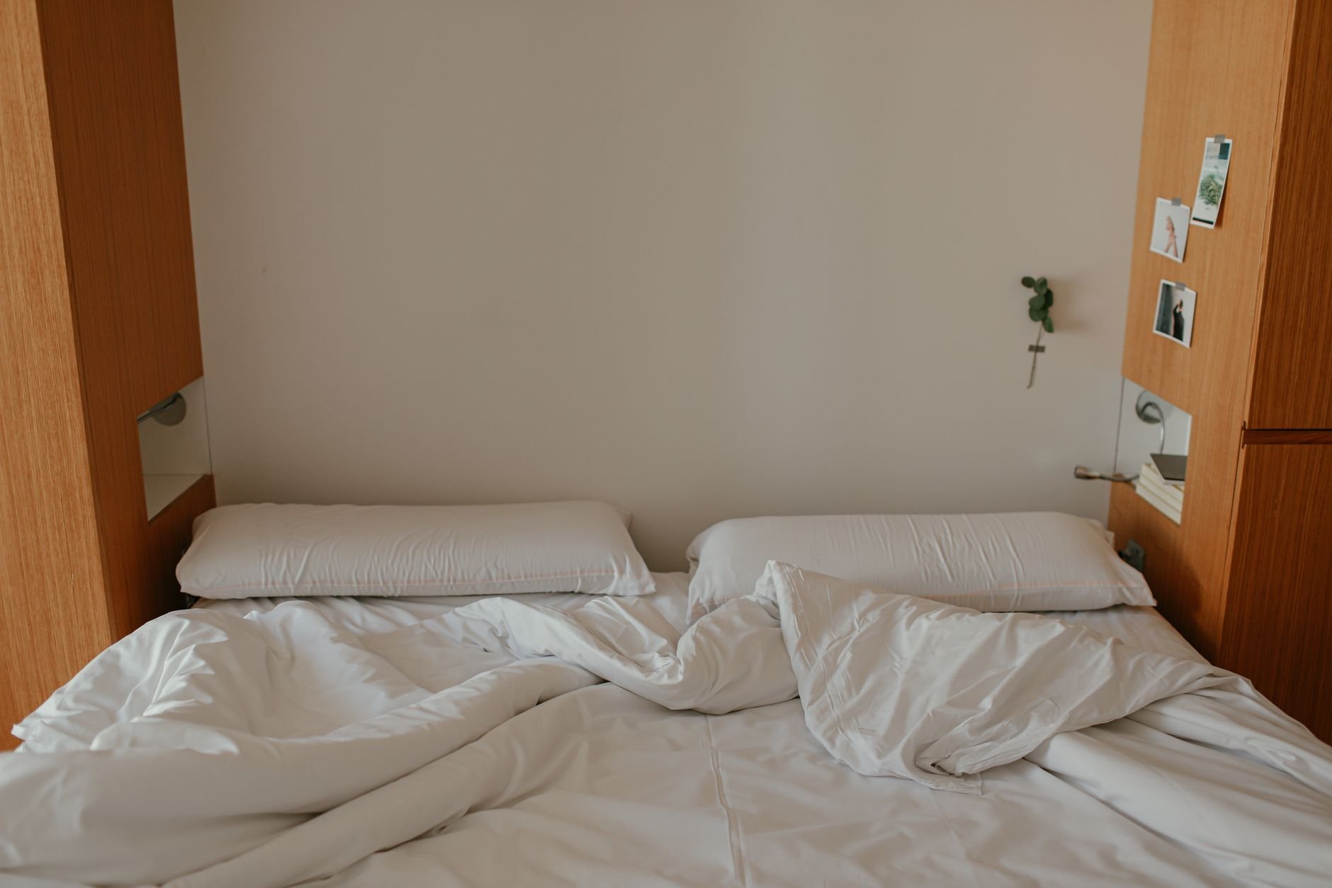 A cozy minimalist bedroom with white linen, soft pillows and warm morning light